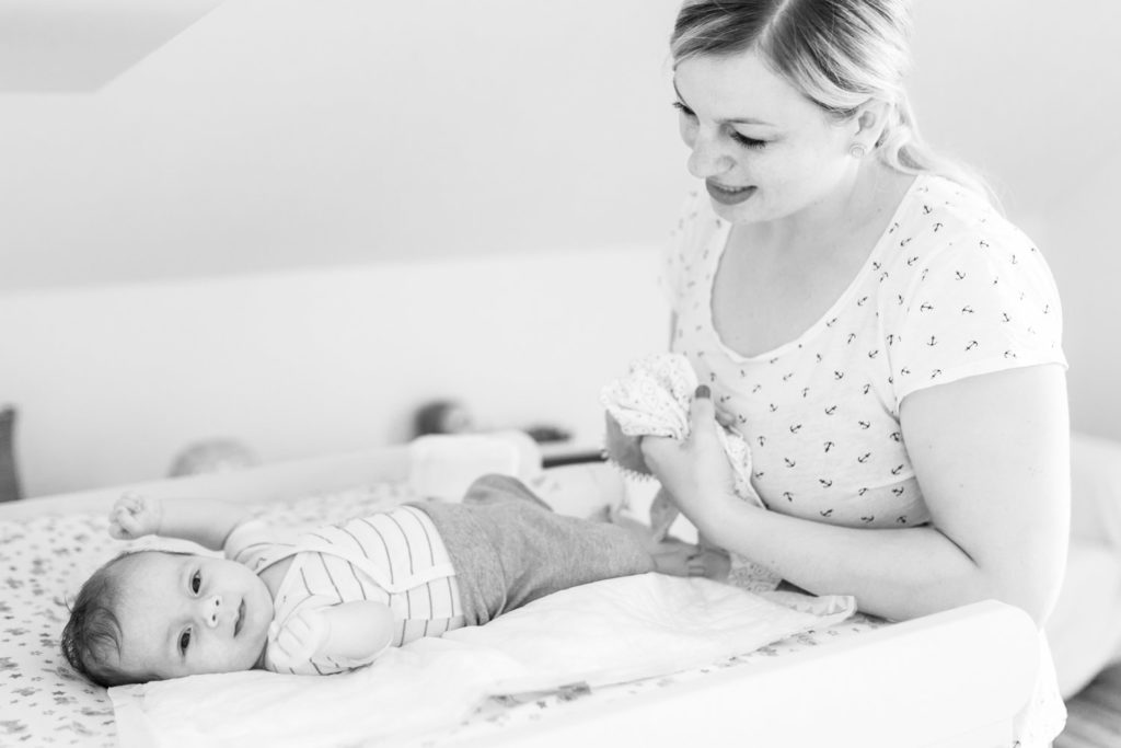 Mama zieht Baby auf dem Wickeltisch an