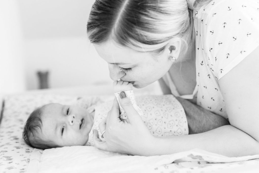 Baby küsst Baby auf die Hand auf dem Wickeltisch