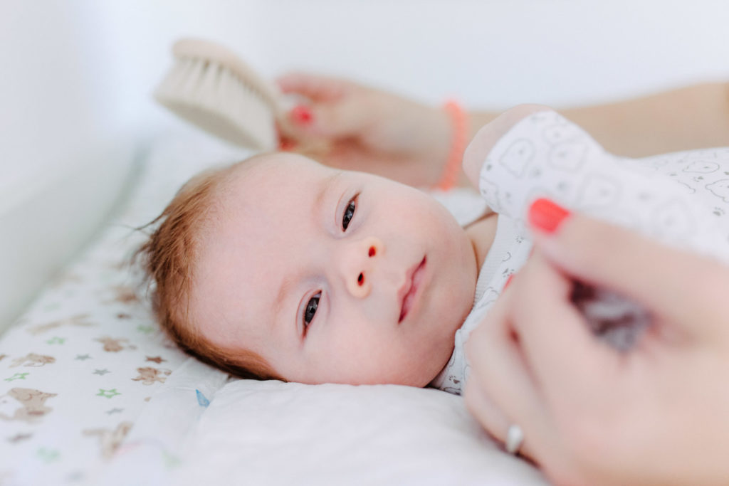 Baby wird gekämmt auf dem Wickeltisch