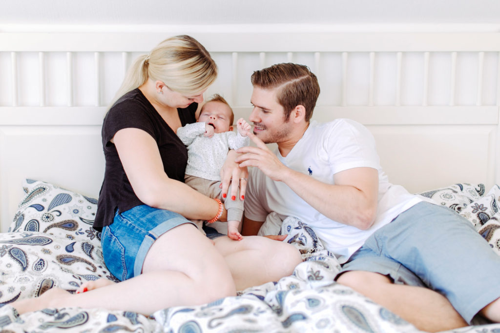 Mama Und Papa mit Baby auf dem Bett