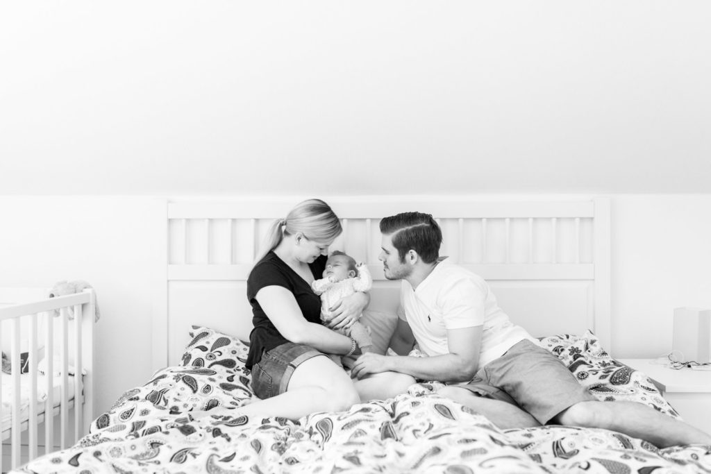 Mama Und Papa kuscheln mit Baby auf dem Bett