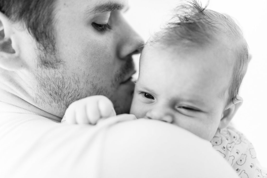 Baby auf Papas arm guckt über die Schulter