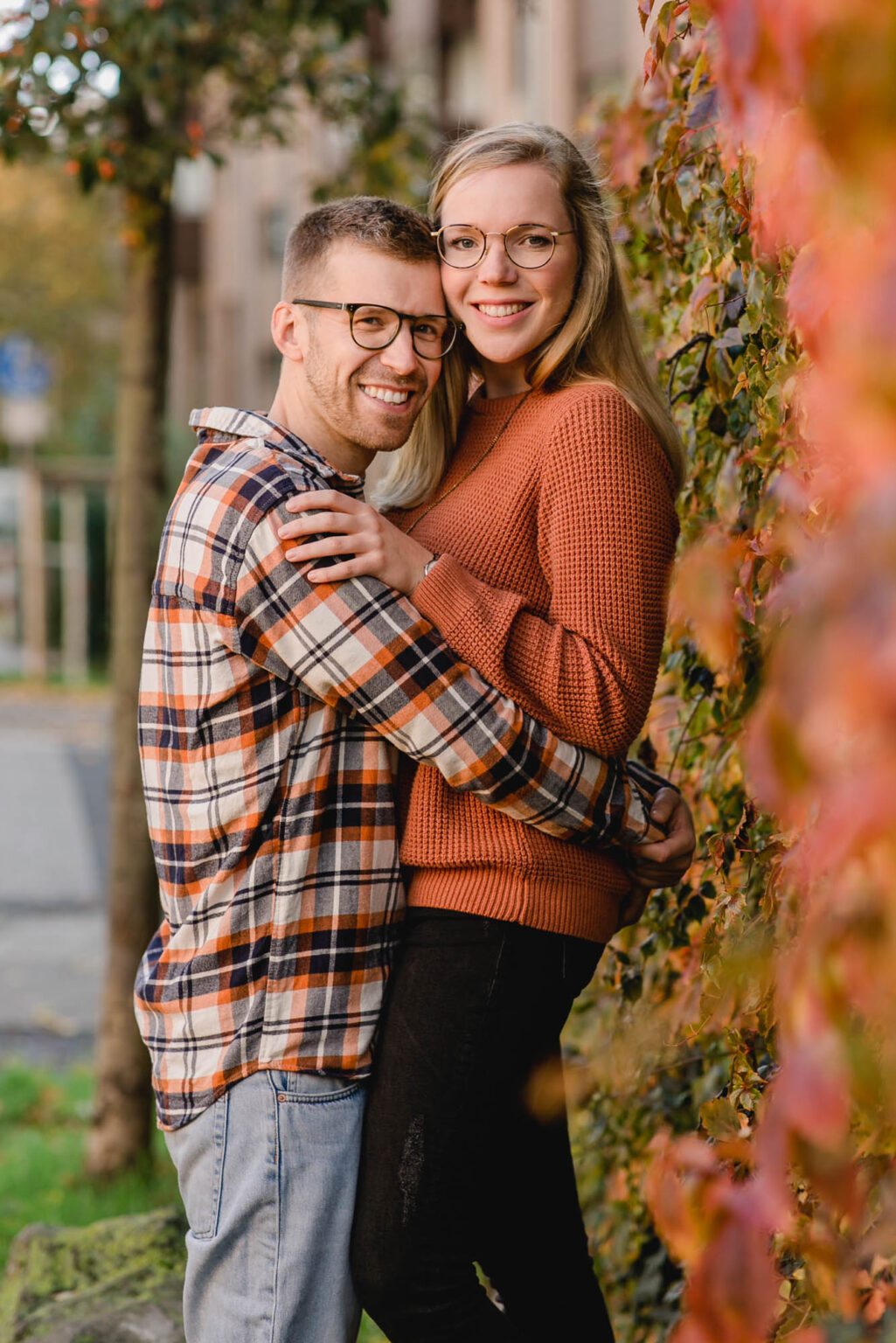 Mann und Frau Arm in Arm an einer bewachsenen Mauer.