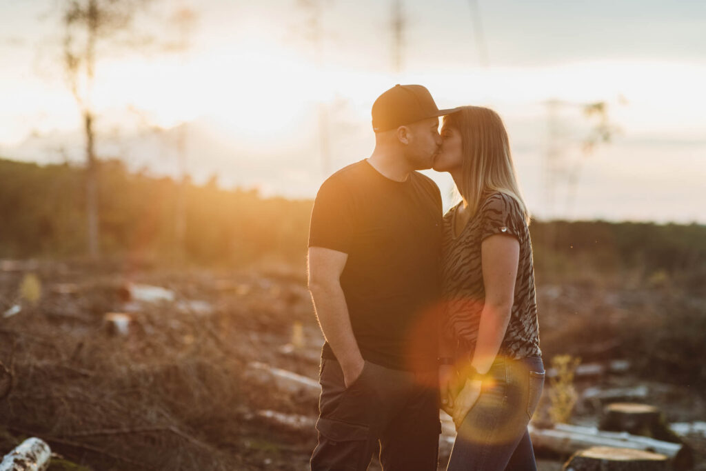 Frau und ein Mann küssen sich im Sonnenuntergang.