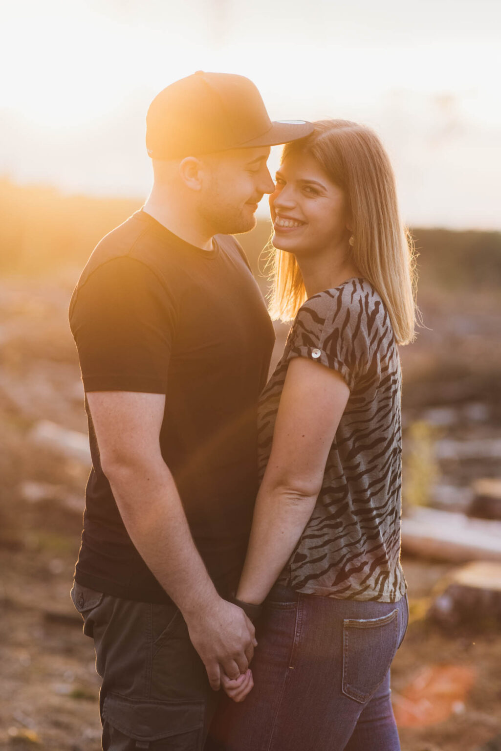 Frau und ein Mann stehen Arm in Arm im goldenen Licht.