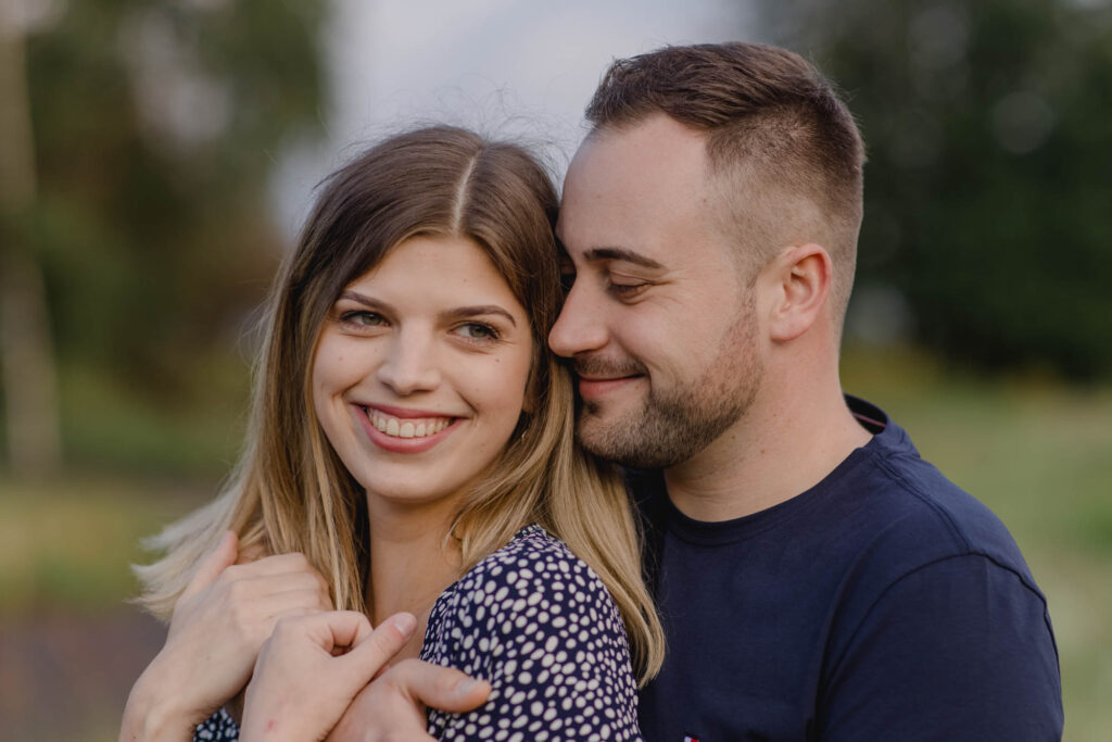 Frau und ein Mann stehen Arm in Arm und lächeln.