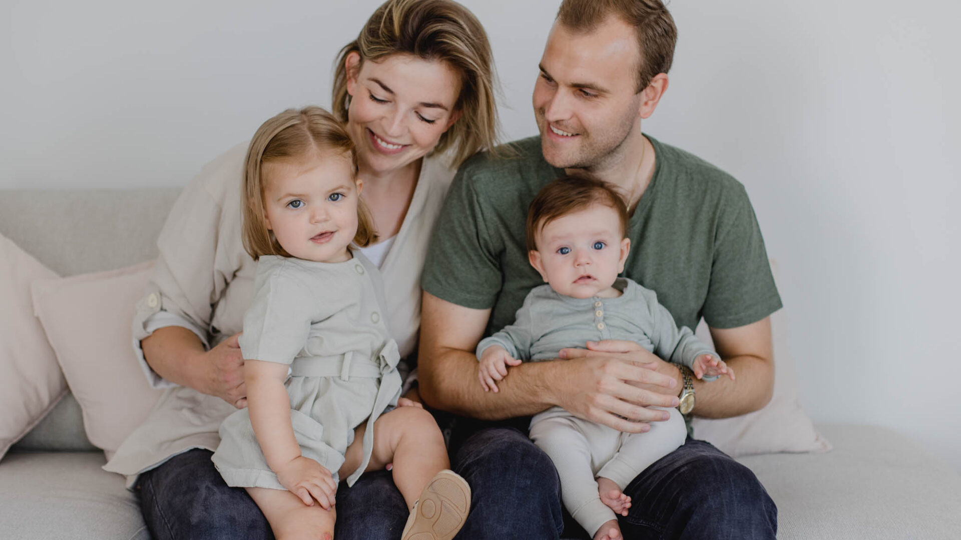 Mutter und Vater mit zwei Kindern auf der Couch.