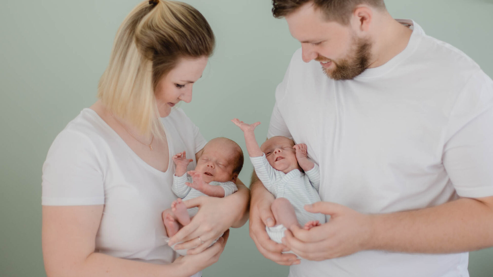 Mann und Frau halten zwei kleine Babys auf dem Arm.