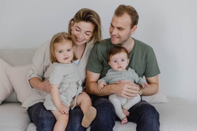 Mutter und Vater mit zwei Kindern auf der Couch.